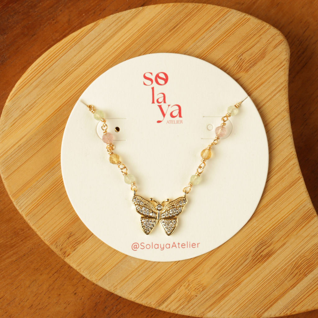 Butterfly necklace on a Solaya Atelier branded card on a wooden surface