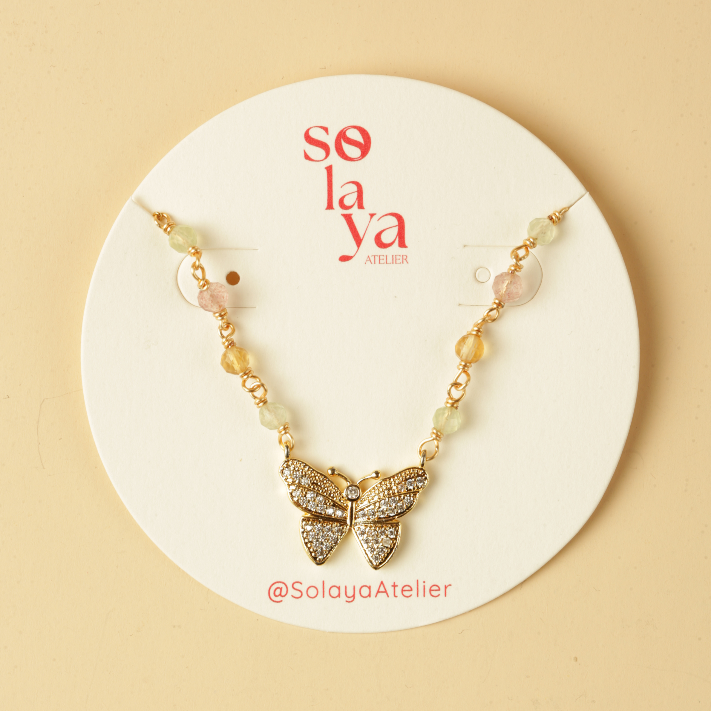 Butterfly necklace on a white card with 'solaya' branding on a beige background