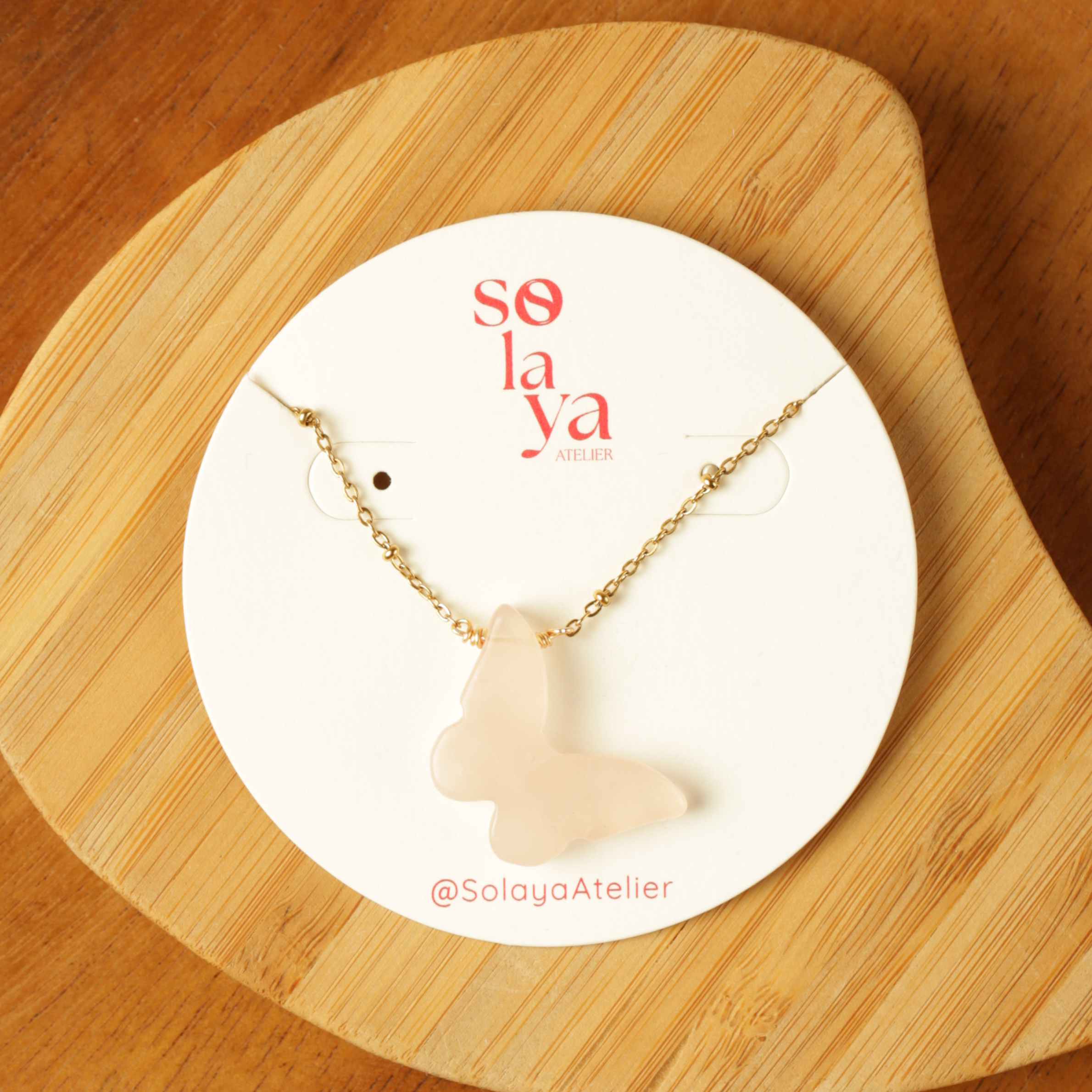 Necklace with a pendant on a Solaya Atelier branded card, placed on a wooden surface.