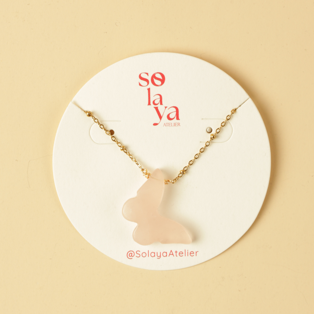 Necklace with a pink cat-shaped pendant on a Solaya Atelier branded card against a beige background